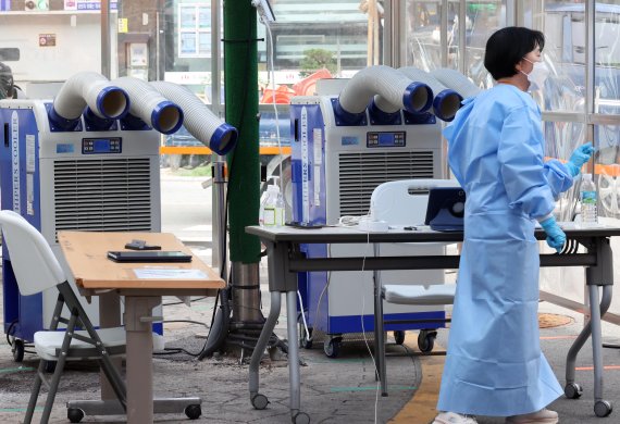 폭염과 함께 코로나19 확진자가 1만9000여명을 기록한 6일 서울 중구보건소 선별진료소에서 의료진이 냉풍기로 더위를 식히고 있다. 사진&#x3D;박범준 기자