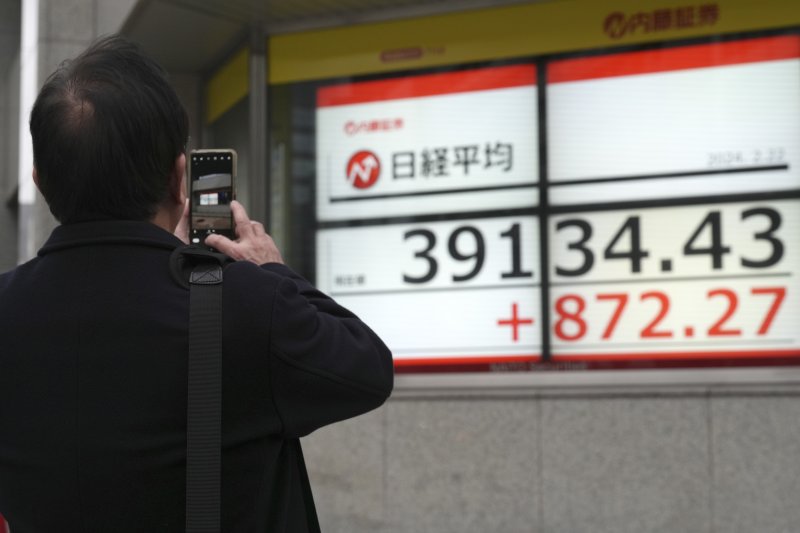 22일 일본 도쿄 시내에서 행인이 증시 현황판을 휴대전화로 찍고 있다. 연합뉴스 제공