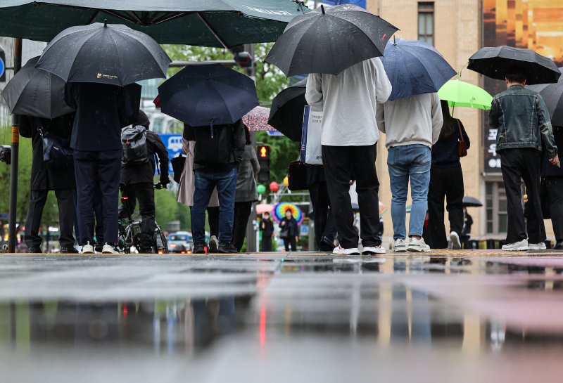 서울 종로구 세종대로사거리에서 우산을 쓴 시민들이 발걸음을 옮기고 있다.   뉴스1