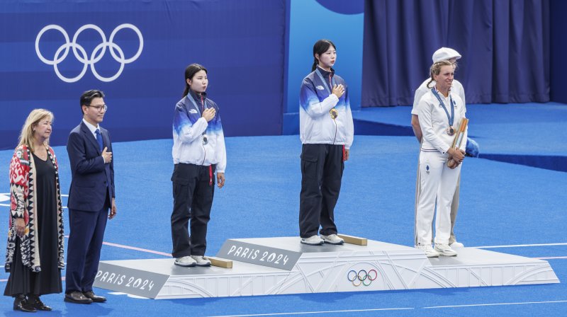 3일(현지시간) 프랑스 파리 레쟁발리드에서 열린 2024 파리올림픽 양궁 여자 개인전 결승에서 금메달을 딴 한국의 임시현(가운데)과 은메달을 획득한 남수현(왼쪽)이 시상식에서 애국가를 들으며 게양되는 두 개의 태극기를 바라보고 있다. 연합뉴스