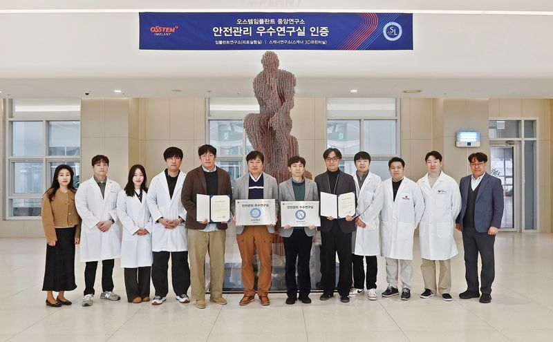 지난 12일 서울 강서구 <span id='_stock_code_048260' data-stockcode='048260'>오스템임플란트</span> 트윈타워 연구동 로비에서 윤지훈 임플란트연구소장(사진 왼쪽에서부터 여섯번째)과 김진태 스캐너연구소장(사진 왼쪽에서부터 일곱번째)을 비롯한 연구소 관계자들이 과학기술정보통신부의 ‘안전관리 우수연구실’ 인증서 및 명판을 들고 기념촬영을 하고 있다. 오스템임플란트 제공