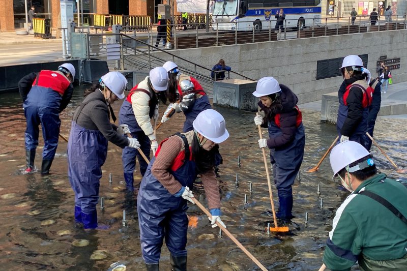 지난 20일 서울시 중구 청계천 일대에서 롯데마트와 슈퍼 임직원들이 청계천 바닥에 낀 녹조류와 퇴적물을 제거하고 있다. <span id='_stock_code_023530' data-stockcode='023530'>롯데쇼핑</span> 제공