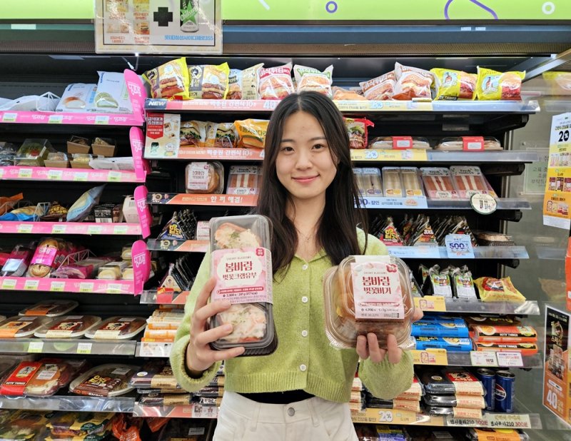 모델이 CU에서 새로 출시한 벚꽃크랩유부, 벚꽃버거 제품을 선보이고 있다. <span id='_stock_code_282330' data-stockcode='282330'>BGF리테일</span> 제공