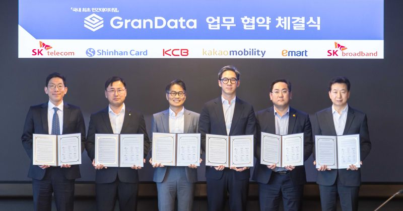박준 <span id='_stock_code_034730' data-stockcode='034730'>SK</span>T AI Intelligence사업본부장(부사장), 박창석 신한카드 전략사업그룹장(부사장), 고현덕 KCB CB사업부문장, 장성욱 카카오모빌리티 미래사업실장(부사장), 정우진 <span id='_stock_code_139480' data-stockcode='139480'>이마트</span> 마케팅 담당, 이철행 <span id='_stock_code_033630' data-stockcode='033630'>SK브로드밴드</span> AT/DT개발실장(왼쪽부터)이 지난 3일 업무 협약을 맺고 기념 촬영하는 모습. SKT 제공