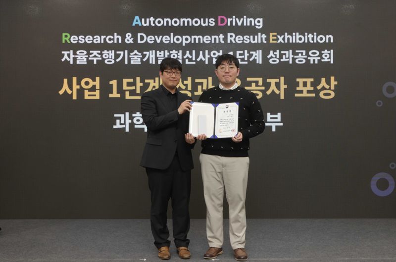 지난 4일 일산킨텍스에서 열린 ‘자율주행기술개발혁신사업’ 1단계 성과공유회에서 <span id='_stock_code_035720' data-stockcode='035720'>카카오</span>모빌리티 홍승환 책임연구원(오른쪽)과 과학기술정보통신부 송창종 디바이스AX혁신팀장이 기념촬영을 하고 있다. 카카오모빌리티 제공