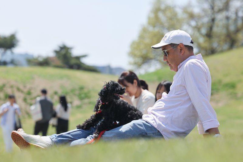 서울 한낮 기온이 24도까지 오르며 포근한 날씨를 보인 지난달 20일 서울 송파구 올림픽공원에서 한 시민이 반려견과 나들이를 즐기고 있다. 연합뉴스