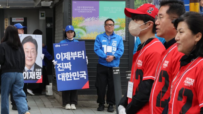 제21대 대통령 공식 선거운동 둘째 날인 13일 서울 서대문구 한 거리에서 기호 1번 더불어민주당 이재명, 2번 국민의힘 김문수 후보 선거운동원들이 시민들에게 인사하고 있다. 연합뉴스