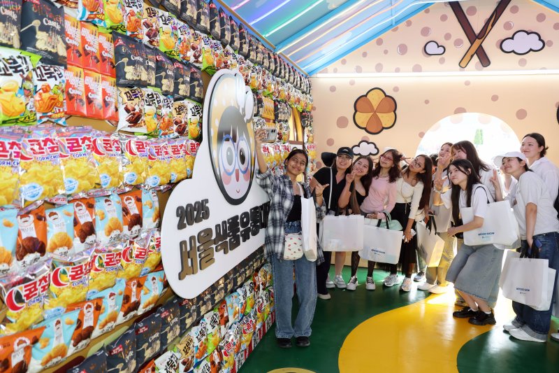 파이낸셜뉴스가 28일 서울 중구 서울광장에서 개최한 '2025 서울식품유통대전(K푸드쇼)'의 포토존인 대형 과자집을 찾은 경복대 어학당 외국인 학생들이 K스낵 전시물을 보며 기념촬영을 하고 있다. 사진=서동일 기자