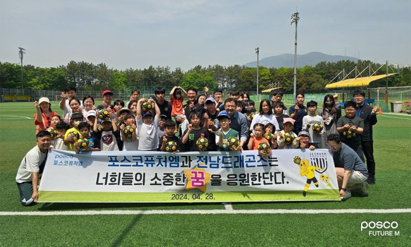 포스코퓨처엠 광양양극소재실 임직원들과 전남드래곤즈 선수들이 지난해 4월 금호동 송죽구장에서 세풍·여천지역 어린이를 위한 축구 클리닉을 실시한 후 참가자 및 가족들과 함께 기념사진을 촬영하고 있다. 포스코퓨처엠 제공