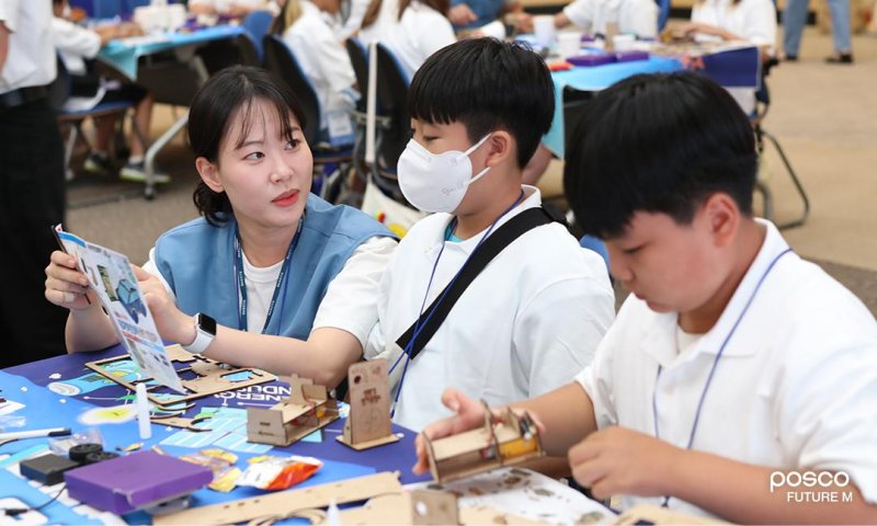 포스코퓨처엠 직원이 푸른꿈 환경캠프에 멘토로 나서 어린이와 함께 전기차 모형을 제작하고 있다. 포스코퓨처엠 제공