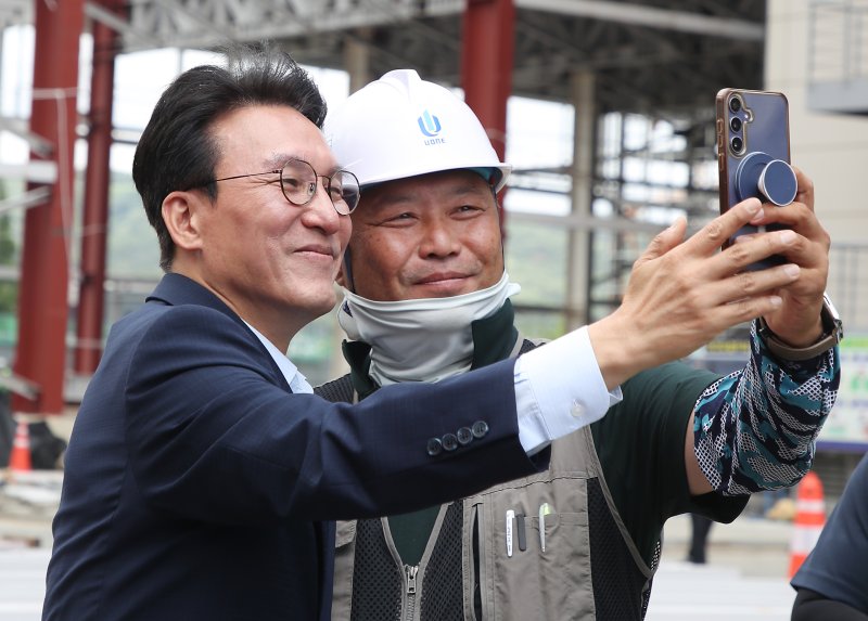김민석 국무총리가 11일 오전 경북 경주화백컨벤션센터를 찾아 APEC 정상회의 미디어센터 건립 현장에서 무더위와 싸우며 일하는 근로자들을 격려한 뒤 이들의 요청에 기념촬영하고 있다. 뉴스1화상