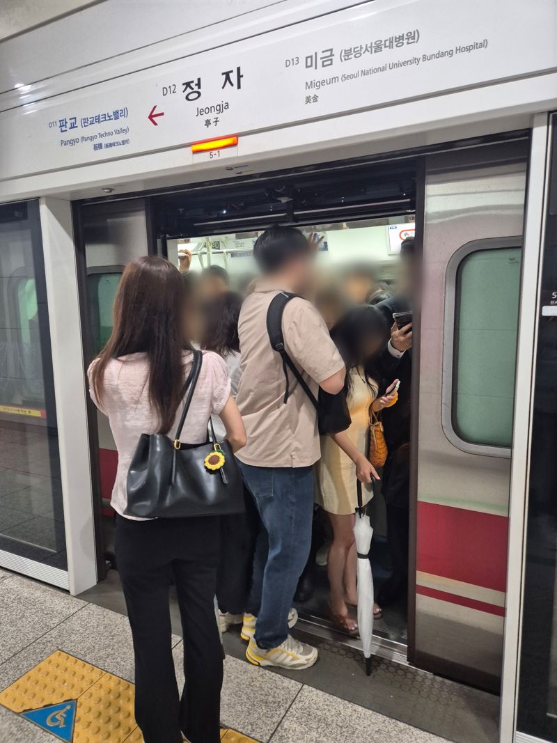 비에 젖은 우산을 손에 든 채 몸을 잔뜩 웅크리고 간신히 열차에 올라타는 직장인들. 사진=김예지 기자