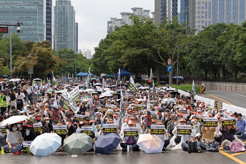교과서발전위원회와 디지털교과서(AIDT) 발행사 등 교육계 관계자들이 21일 서울 여의도 국회 앞에서 열린 총궐기대회에서 AI 디지털교과서의 법적 지위 격하에 반대하며 정책 철회를 요구하고 있다. 천재교과서 제공