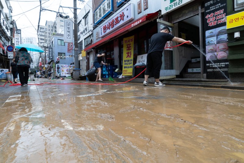 지난 13일 오후 서울 은평구 연신내역 인근 상가 거리에서 상인들이 폭우로 인해 더러워진 거리를 청소하고 있다. 2025.8.13 /사진=뉴스1