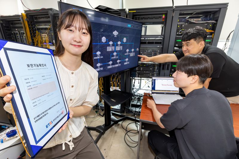 <span id='_stock_code_030200' data-stockcode='030200'>KT</span>와 <span id='_stock_code_056360' data-stockcode='056360'>코위버</span> 직원이 양자키분배 기술 적용 장비를 점검하며 보안 인증서를 소개하는 모습. KT 제공