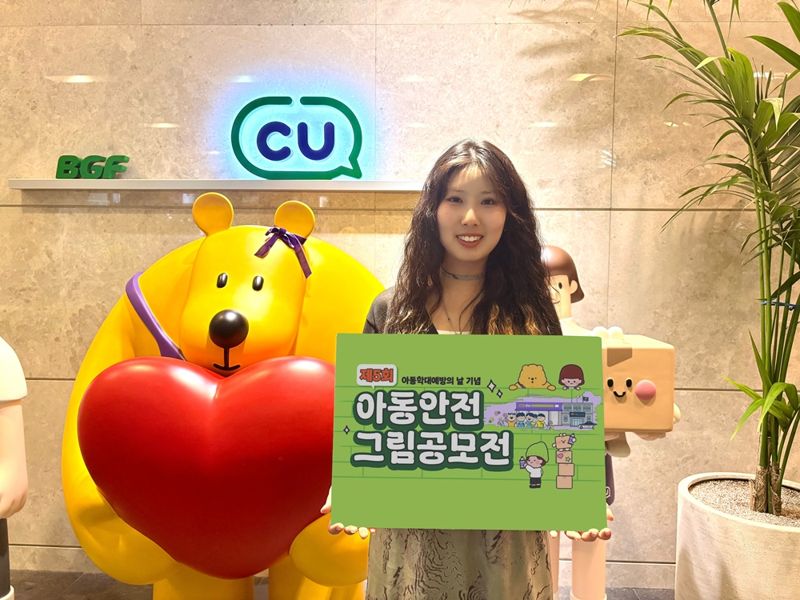 모델이 BGF리테일의 제5회 '아동 안전 그림 공모전' 광고물을 들고 포즈를 취하고 있다. BGF리테일 제공