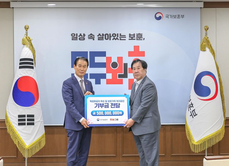 우오현 SM그룹 회장(오른쪽)이 13일 정부세종청사에서 열린 국가보훈부의 전 국민 보훈 기부 프로젝트 '모두의 보훈 드림' 후원금 전달식에서 5억원을 기부한 뒤 권오을 국가보훈부 장관과 기념촬영을 하고 있다. SM그룹 제공