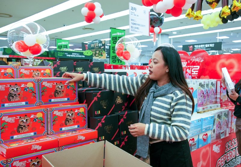‘빼빼로 에이전트 피' 활동에 참여한 한 외국인 참가자가 마트에 진열된 빼빼로를 배경으로 콘텐츠 촬영을 하고 있다. 롯데웰푸드 제공