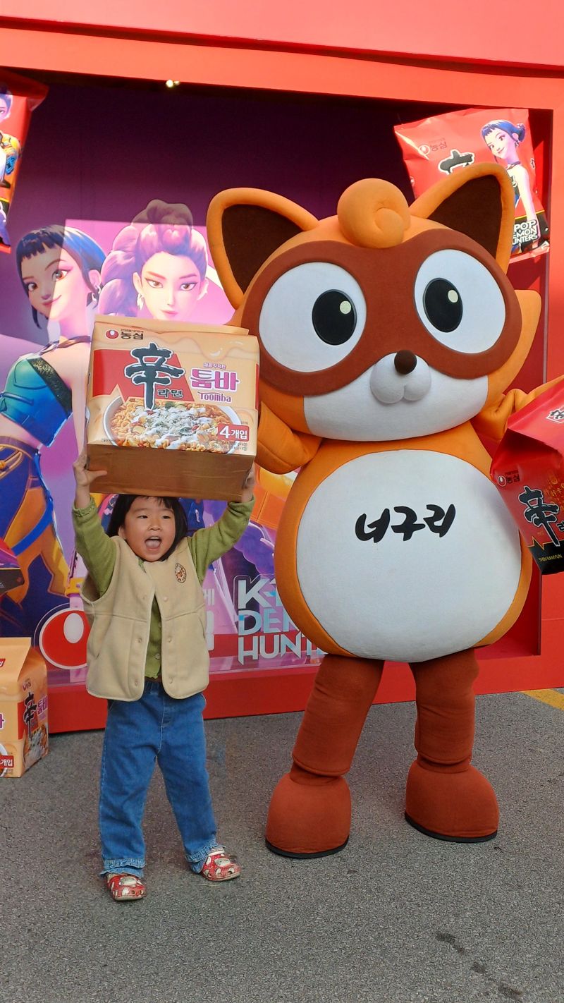 지난 7일 경상북도 구미시에서 열린 '2025 구미라면축제'에 참석한 어린이가 농심 너구리 캐릭터와 기념촬영을 하고 있다. 사진=이환주 기자 