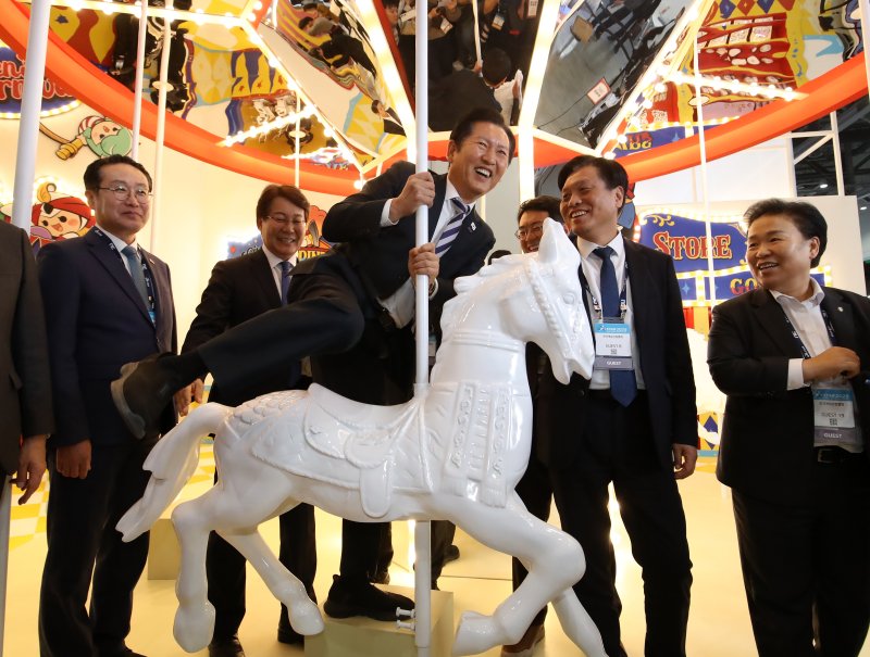 정청래 더불어민주당 대표가 14일 오후 부산 해운대구 벡스코 열린 국내 최대 게임전시회 &#39;지스타 2025&#39;에서 <span id='_stock_code_069080' data-stockcode='069080'>웹젠</span> 부스를 찾아 회전목마에 올라 타고 있다. 뉴스1.