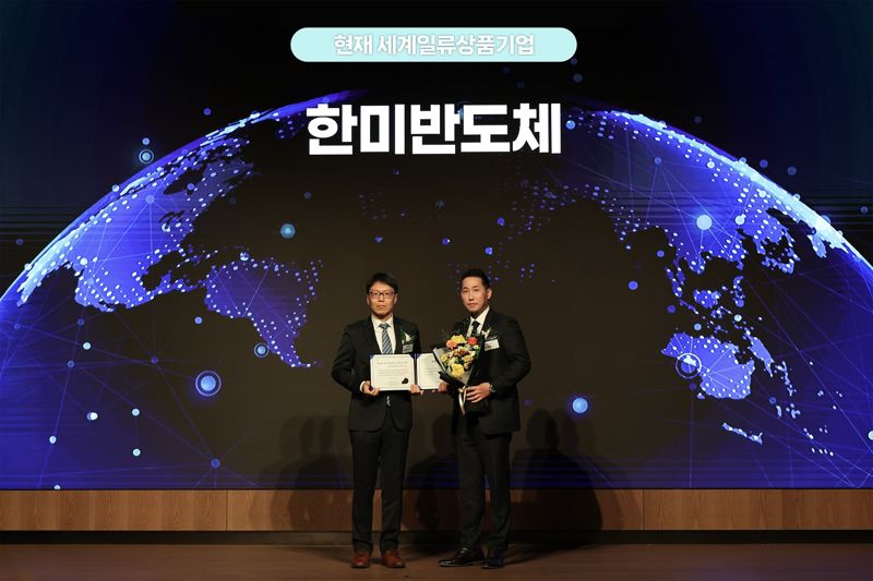 방효영 <span id='_stock_code_042700' data-stockcode='042700'>한미반도체</span> 상무(오른쪽)가 지난 18일 열린 ‘2025 세계일류상품 인증서 수여식’에서 최연우 산업통상부 중견기업정책관 기념촬영을 하고 있다. 한미반도체 제공