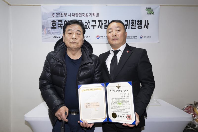 국유단장 직무대리 조해학 중령(육군)은 고 구자길 일병의 유가족인 남동생 구자천(왼쪽)에게 고인의 신원확인 통지서와 함께 호국영웅 귀환 패, 유품 등이 담긴 '호국의 얼 함(函)'을 전달했다. 국방부 제공