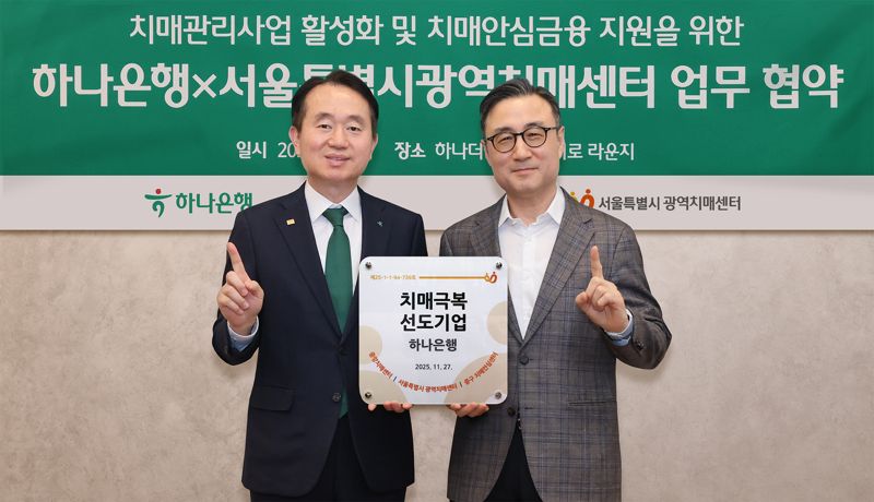 하나은행은 지난 27일 서울 중구 하나더넥스트 을지로 라운지에서 서울특별시광역치매센터와 &#39;치매관리사업 활성화 및 시니어 맞춤 치매안심금융 지원을 위한 업무협약&#39;을 체결했다. 이날 협약식에 참석한 김영훈 하나은행 자산관리그룹 부행장(사진 왼쪽)과 이동영 서울특별시광역치매센터장이 &#39;치매극복선도기업’ 현판을 전달하고 기념촬영을 하고 있다. 하나은행 제공