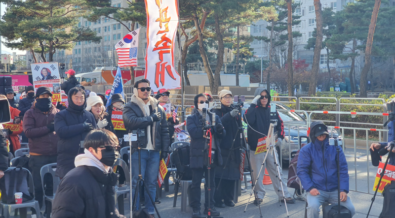 계엄 1년을 맞아 보수 시민단체인 신자유연대가 국회의사당역 3번 출구 앞에서 '이재명 정부 규탄' 집회를 열었다. 집회 참가자들이 국기에 대한 경례를 하고 있다. 사진=최승한 기자