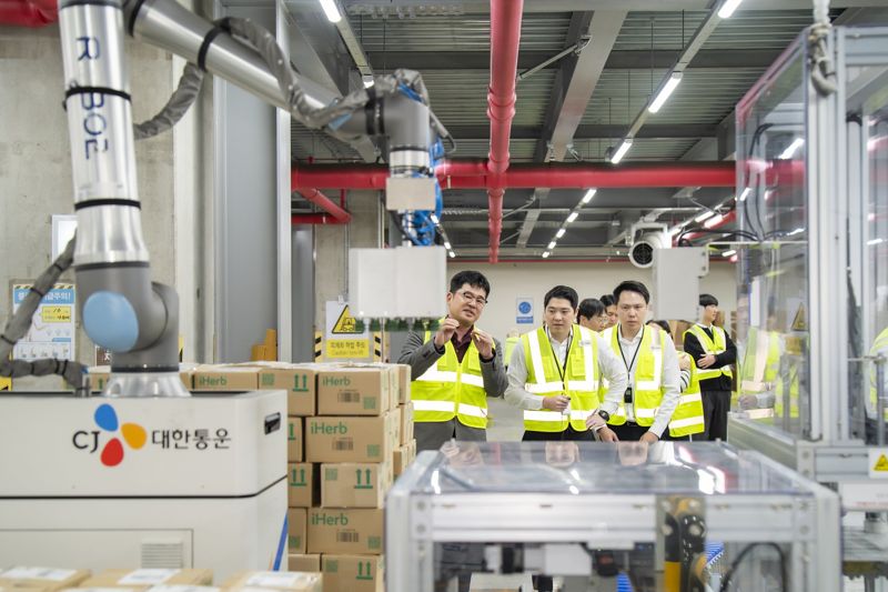 <span id='_stock_code_000120' data-stockcode='000120'>CJ대한통운</span> 인천 GDC를 방문한 태국 최대 유통사 CP 엑스트라 경영진들이 박스를 자동 분류해 파렛트에 쌓는 &#39;이동형 로봇 팔레타이저&#39;에 대해 설명을 듣고 있다.