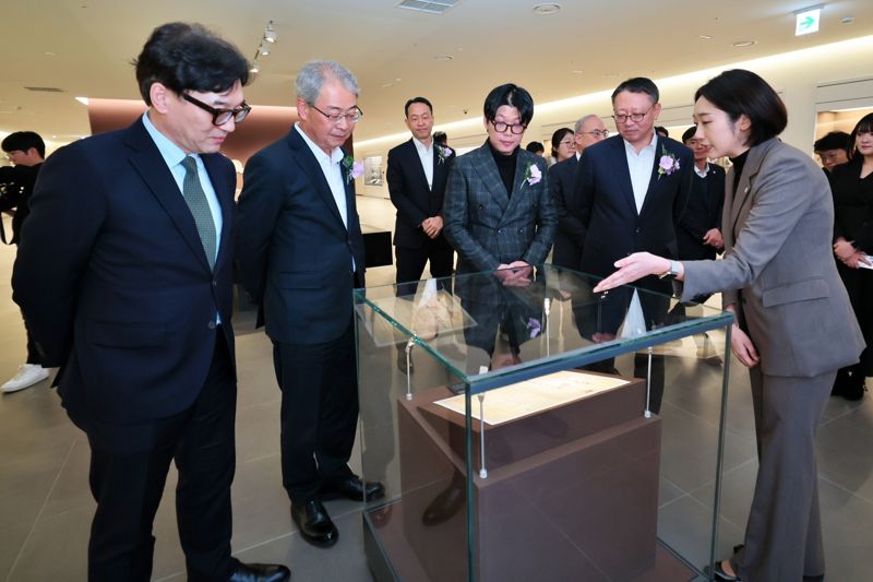 임종룡 우리금융그룹 회장(앞줄 왼쪽 두번째부터), 고 박경리 작가 외손자 김세희 토지문화재단 이사장, 정진완 우리은행장이 서울 중구 '우리1899'에서 서울시 지정문화재인 ‘대한천일은행 창립청원서’에 대한 설명을 듣고 있다. 우리금융지주 제공