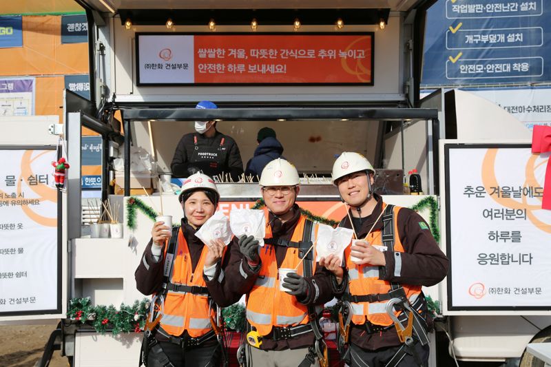 ㈜<span id='_stock_code_000880' data-stockcode='000880'>한화</span> 건설부문 건설현장 근로자들이 '찾아가는 겨울간식차'의 호빵과 어묵을 즐기고 있다. ㈜한화 건설부문 제공